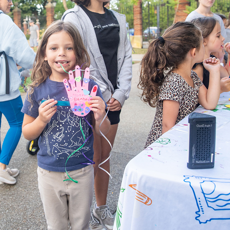 A young child holds up a craft they made